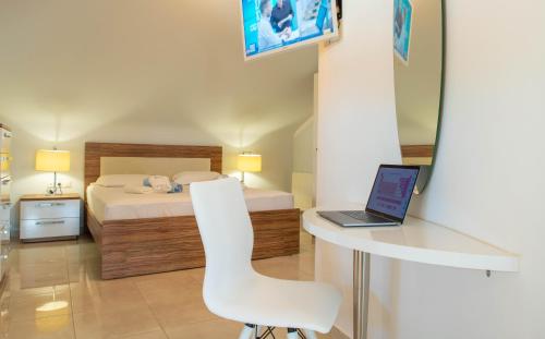 a bedroom with a bed and a desk with a laptop at Oniro Luxury Villas in Toroni