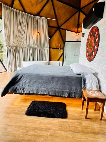 a bedroom with a large bed and a table at Chales Cabana Garden in Monte Verde