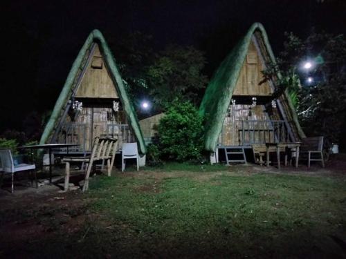 twoangularangular dwellings with tables and chairs at night at Casa de Robles Tanay Rizal in Tanay