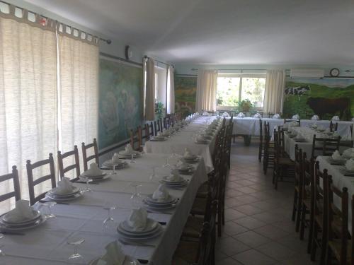 a long dining room with tables and chairs with white tablecloths at La Quercia in Arbus