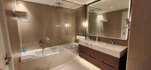a bathroom with a tub and a sink and a mirror at Address Fujairah beach and resort Residence in Fujairah