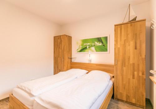 a bedroom with a bed and a wooden cabinet at "Ferienwohnug Bambergers" Ferienwohnung Bamberger s in Büsumer Deichhausen