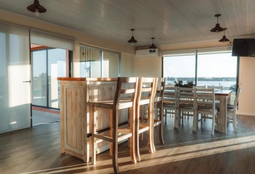 comedor con mesa, sillas y ventanas en Terrazas del Ayuí en Concordia