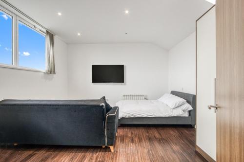 um quarto com um sofá, uma cama e uma televisão em Stylish Studio by Heathrow Airport em Londres
