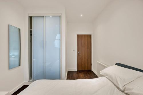 1 dormitorio con 1 cama y puerta corredera de cristal en Modern 1 Bed by Heathrow Airport en Londres