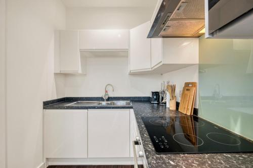 a kitchen with white cabinets and a sink at Modern 1 Bed by Heathrow Airport in London
