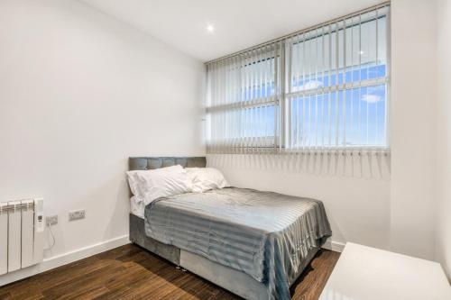 a white bedroom with a bed and a window at Fantastic 1 Bed by Heathrow Airport in London