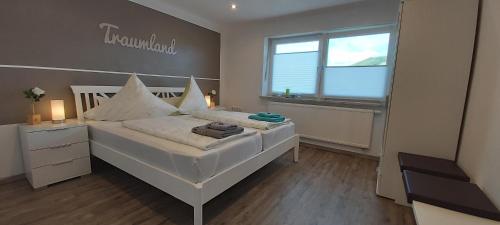 een slaapkamer met een groot wit bed en een raam bij FeWo Hafner "Zuhause mit Ausblick" in Schnaittach