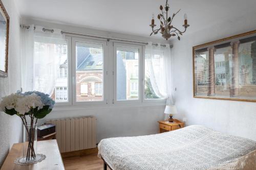 een slaapkamer met een bed en een vaas met bloemen op een tafel bij Le Petit Pélican in Le Tréport