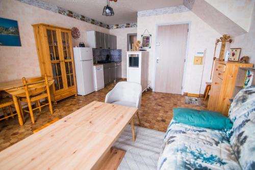 een woonkamer met een houten tafel en een keuken bij Les Campanules in Saint-Léger-les-Mélèzes