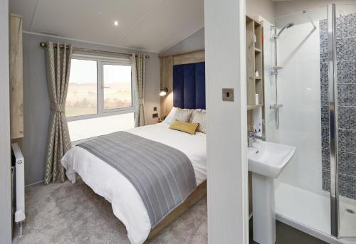 a bedroom with a bed and a sink and a window at Machrihanish Holiday Park in Campbeltown
