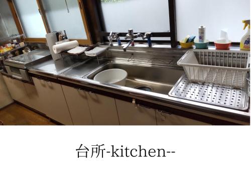 a kitchen with a sink and a dish drying rack at 古民家柚子季 in Tonami