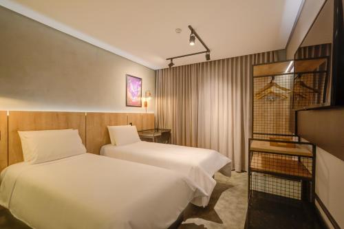 a hotel room with two beds and a television at Slaviero Ponta Grossa in Ponta Grossa