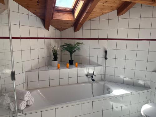 a white tub in a bathroom with a wooden ceiling at the Jad B&B in Comoret