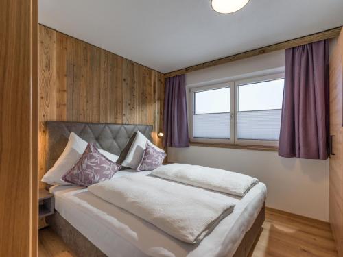 a bedroom with a bed with purple curtains and a window at Alps Holaus in Aschau