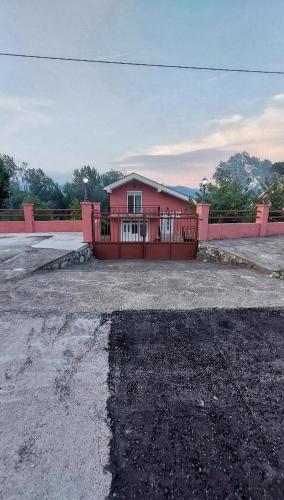 une maison rose avec un portail dans un parking dans l'établissement Apartman Sedmica, à Danilovgrad