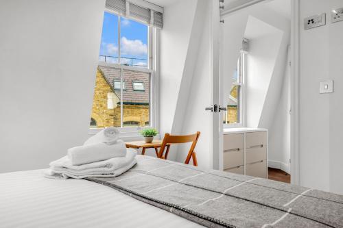 a white bedroom with a bed and a window at Two Bedroom Serviced Apartment in Artillery Lane in London