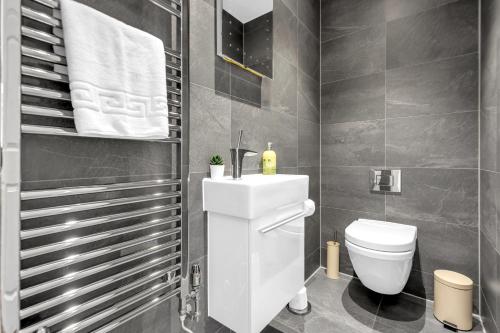 La salle de bains est pourvue de toilettes blanches et d'un lavabo. dans l'établissement Two Bedroom Serviced Apartment in Artillery Lane, à Londres