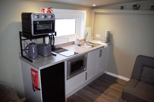 a small kitchen with a microwave and a sink at The Windy Roost in Occumster