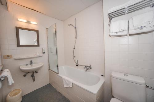 a bathroom with a tub and a sink and a toilet at Hotel Louisa in Ostend