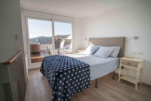 a bedroom with a bed and a large window at Penthouse Cortey in Calella de Palafrugell