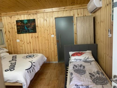 duas camas em um quarto com paredes de madeira em מפגש הדובדבן em Buq‘ātā
