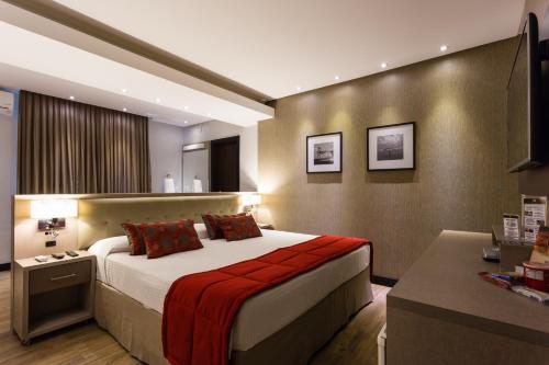 a bedroom with a large bed and a desk at Faial Prime Suítes in Florianópolis