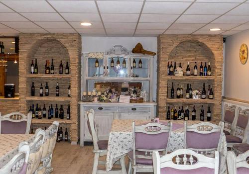 - un restaurant avec une table, des chaises et des bouteilles de vin dans l'établissement A SZELLŐ, à Domonyvölgy