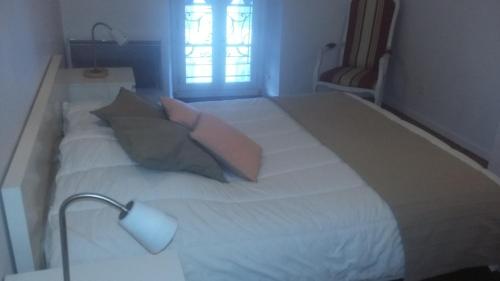 a large white bed with pillows and a lamp at Appartement FARIO in Ax-les-Thermes