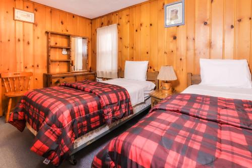 two beds in a room with wooden walls at Fishing Paradise in Phelps
