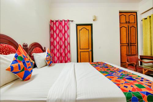 a bedroom with a large white bed with colorful pillows at FabHotel Singh Suite in Gurgaon