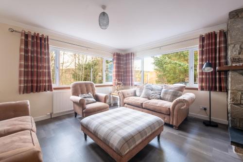 a living room with couches and chairs and windows at Silverbridge Lodge in Garve