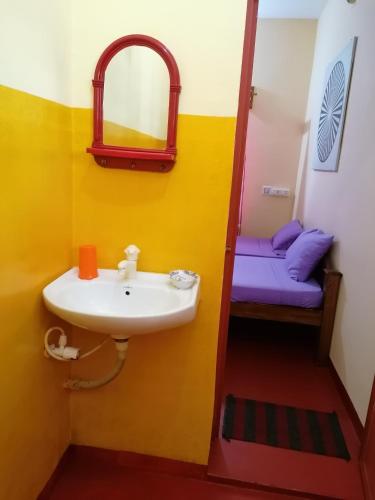 a bathroom with a sink and a mirror and a bed at Sukriti beach Resort in Varkala