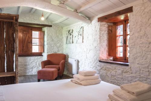 a room with a bed and a chair and towels at Houmi A Ponte in Boimorto