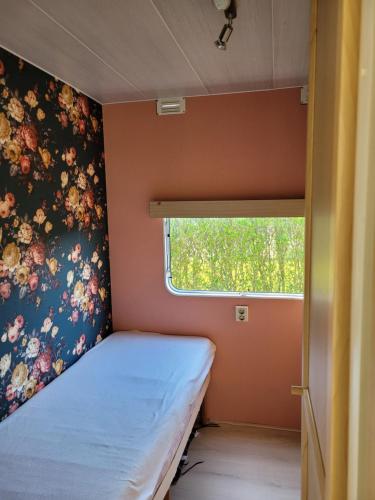 Habitación pequeña con cama y ventana en Camping De Blauwe Reiger, en Pieterzijl