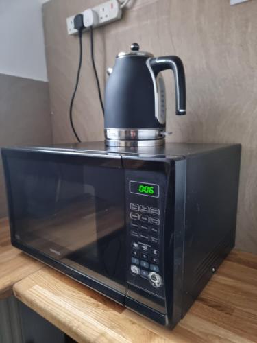 a black microwave with a tea kettle on top of it at George Street Rooms in Hull