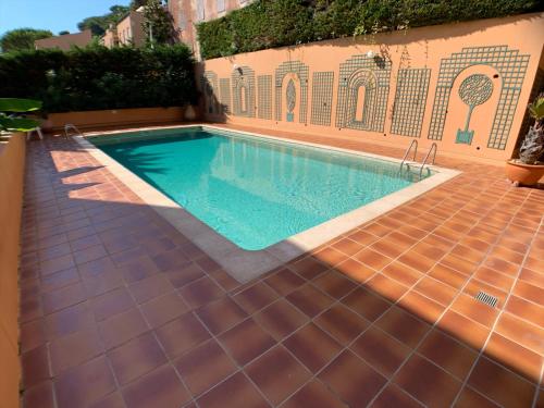 a swimming pool with a tiled floor next to a building at Raffiné appartement in Saint-Jean-Cap-Ferrat