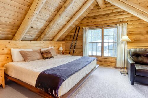 1 dormitorio con 1 cama y 1 silla en una cabaña de madera en Red Pines Log Cabin, en Sunriver