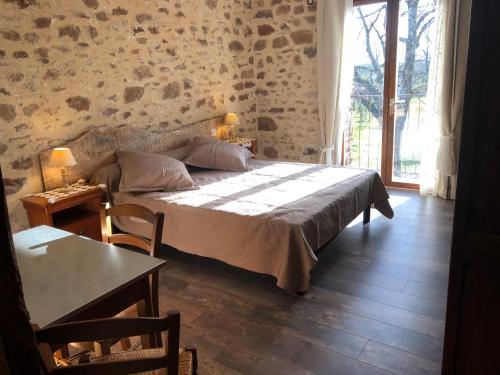 ein Schlafzimmer mit einem großen Bett in einem Zimmer mit einem Tisch in der Unterkunft Maison d'hôtes " Ecuries de St maurice" in Lacapelle-Marival
