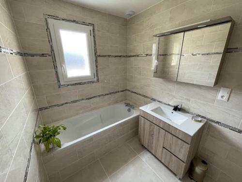 uma casa de banho com uma banheira, um lavatório e um espelho. em Maison neuve proche de la mer em Créances