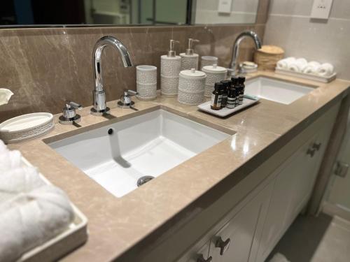 a bathroom counter with a sink with two faucets at Majestay - Luxury Living in Dubai