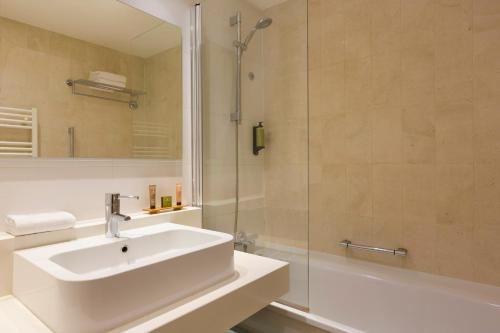 巴黎的住宿－馨樂庭巴黎歌劇院旅館，白色的浴室设有水槽和淋浴。