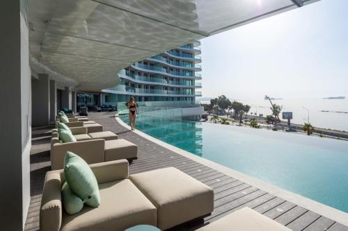 a man standing next to a swimming pool next to a building at Limassol Del Mar in Limassol