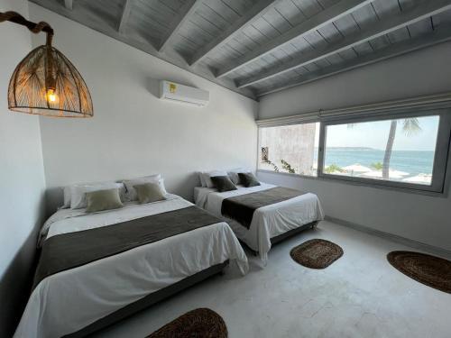 two beds in a room with a view of the ocean at Wala beach club in Cartagena de Indias