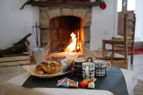 a table with a plate of pastries and coffee cups and a fireplace at La Dimora di Euterpe in Ruviano
