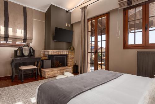 a bedroom with a bed and a desk and a fireplace at GM Luxury Suites Kalavryta in Kalavrita
