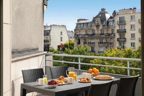 a table with food and fruit on a balcony at Citadines Bastille Marais Paris in Paris