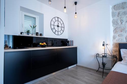 a kitchen with black cabinets and a large clock on the wall at Apartments Sara & Nora in Dubrovnik