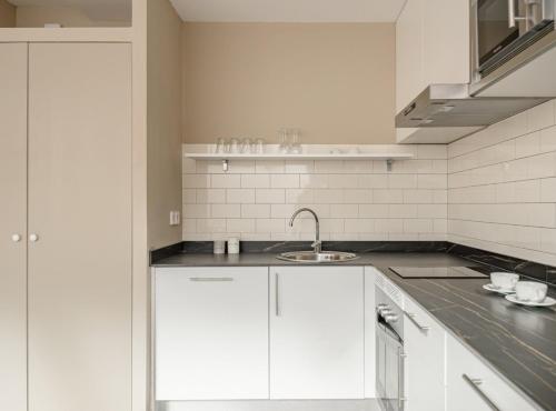 a kitchen with white cabinets and a sink at Home Art Apartments Salamanca in Madrid