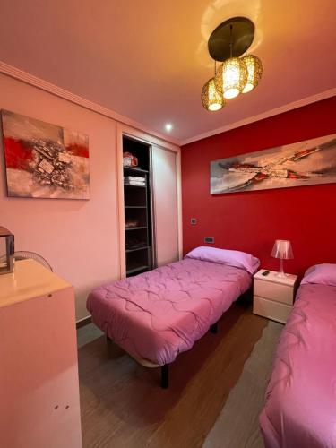 a room with two beds in a room with red walls at Vivienda en El Campello playa in El Campello